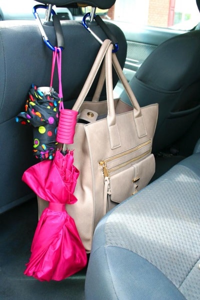 Handbag and umbrellas hanging from a car headrest