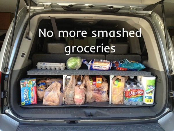 A fold-able shelf filled with groceries inside the trunk of a car