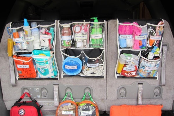 Clear shower caddy's filled with items hanging on the back of the car seats in the trunk of a car